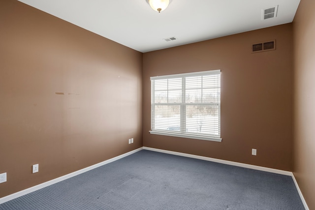 spare room featuring carpet, visible vents, and baseboards