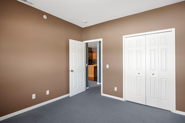 unfurnished bedroom with dark colored carpet, a closet, visible vents, and baseboards