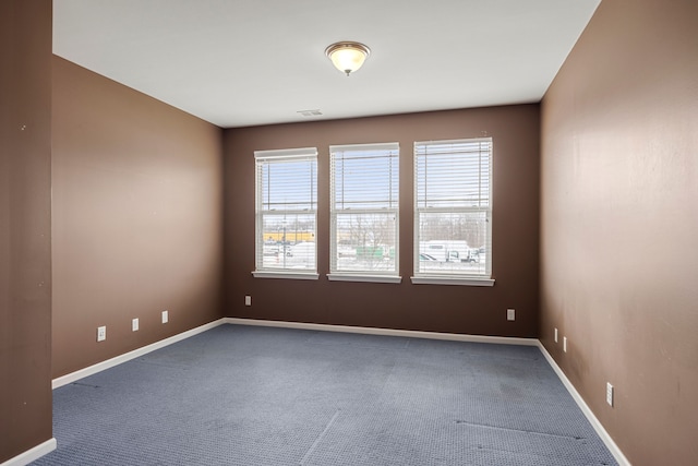 carpeted spare room with visible vents and baseboards