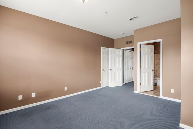 unfurnished bedroom featuring baseboards, visible vents, carpet flooring, and ensuite bathroom