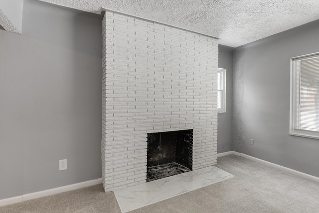 unfurnished living room featuring a brick fireplace, light colored carpet, a textured ceiling, and baseboards