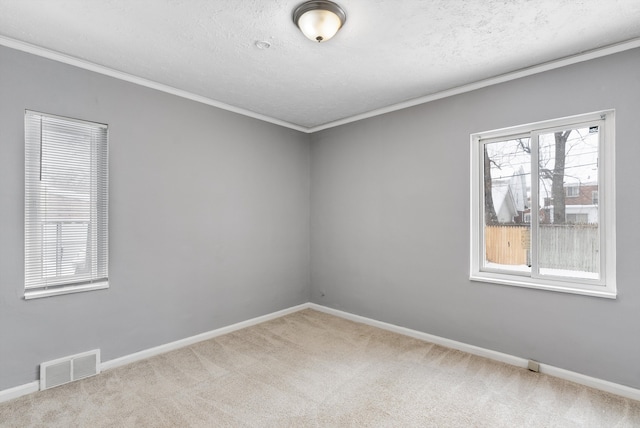 carpeted empty room with baseboards, visible vents, a textured ceiling, and ornamental molding