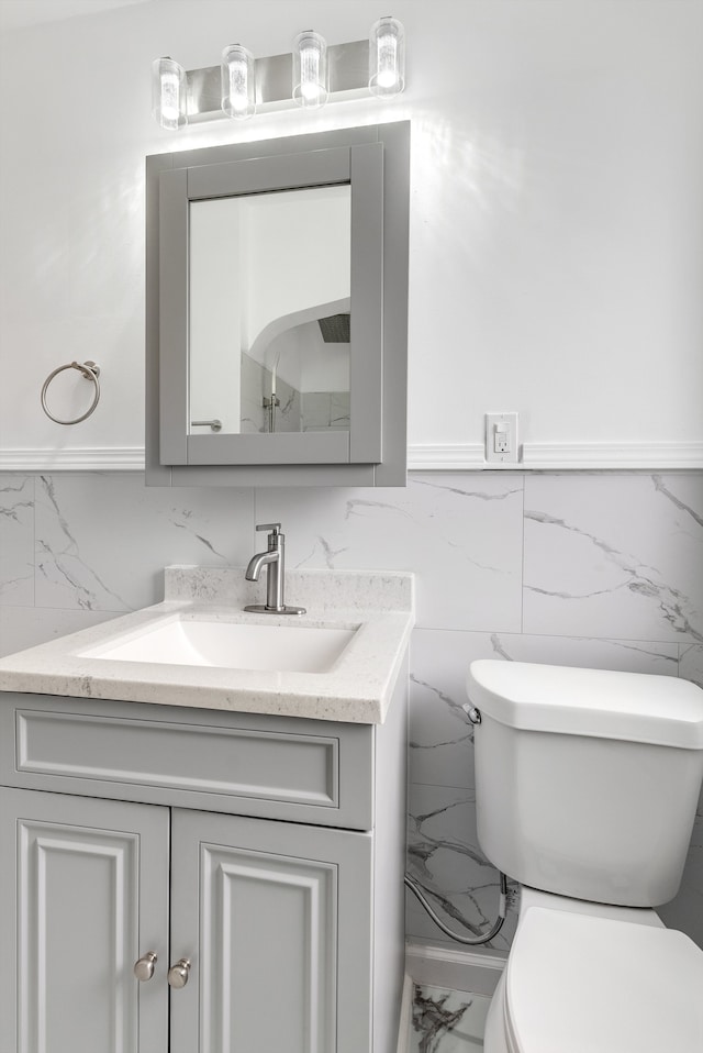 bathroom with toilet, marble finish floor, and vanity