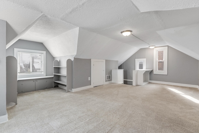 bonus room featuring visible vents, carpet flooring, vaulted ceiling, and a textured ceiling