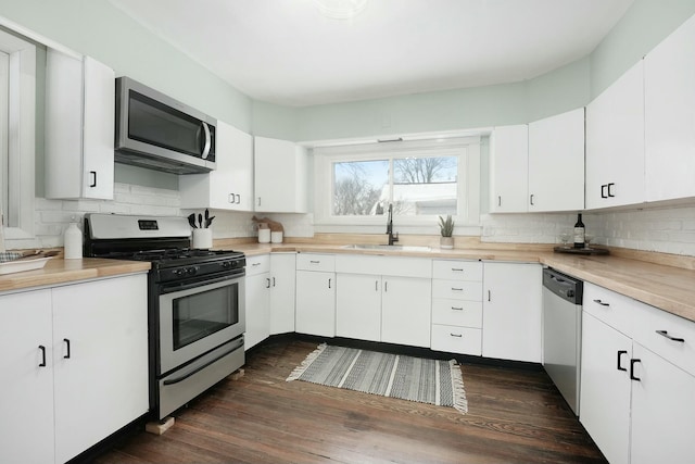 kitchen with tasteful backsplash, light countertops, appliances with stainless steel finishes, white cabinets, and a sink