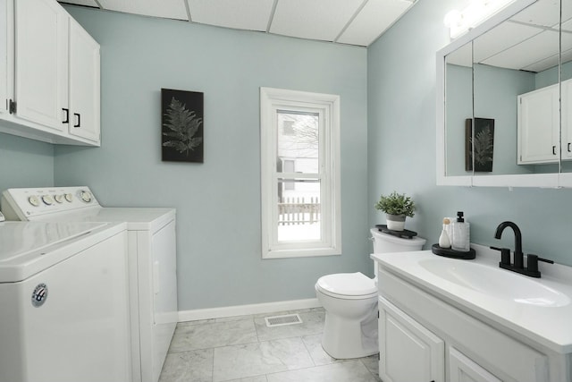 bathroom with toilet, a paneled ceiling, vanity, visible vents, and washer and dryer