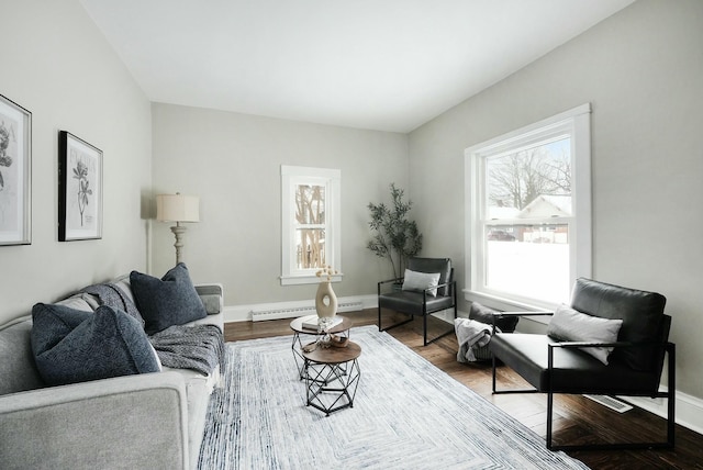 living area featuring a baseboard heating unit, baseboards, and wood finished floors