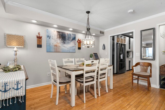 dining room featuring light wood-type flooring, visible vents, crown molding, and baseboards