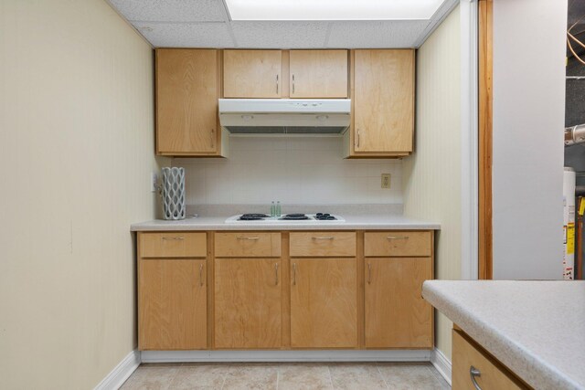 kitchen featuring white cooktop, under cabinet range hood, light countertops, and a drop ceiling