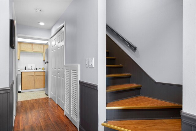 stairs with a wainscoted wall and wood finished floors