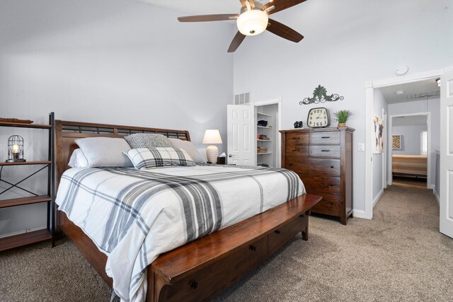 bedroom with carpet, a walk in closet, visible vents, a high ceiling, and baseboards