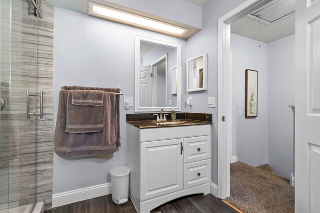 full bath with baseboards, vanity, a shower stall, and wood finished floors