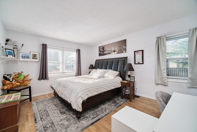 bedroom featuring multiple windows, baseboards, and wood finished floors
