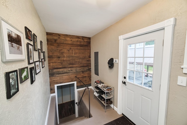 entryway with a textured wall, electric panel, and wooden walls