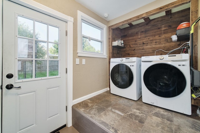 laundry area with wooden walls, laundry area, baseboards, washer and dryer, and stone finish floor