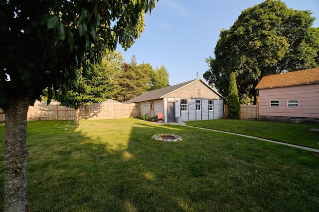 rear view of property featuring a yard, a fenced backyard, and an outdoor structure