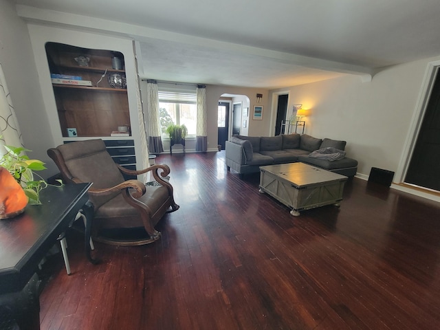 living room featuring dark wood-style floors, arched walkways, and baseboards