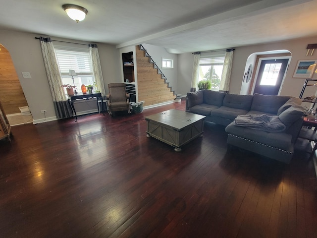 living area with arched walkways, dark wood finished floors, stairway, and baseboards