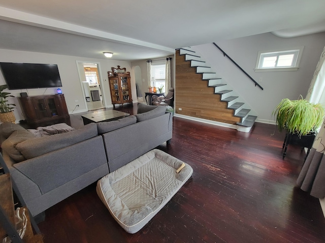 living room with dark wood-type flooring, baseboards, and stairs
