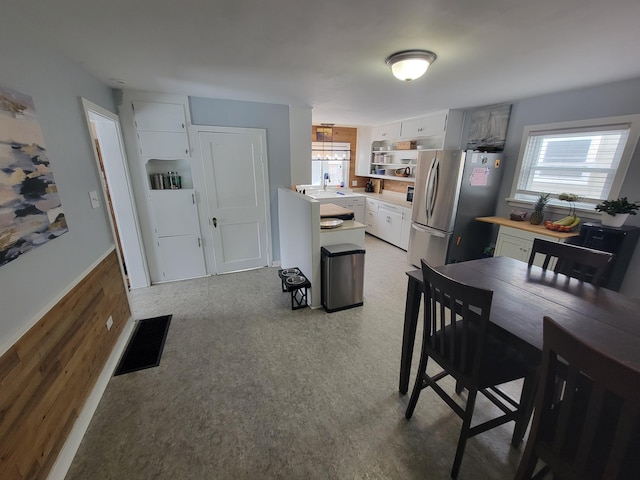 kitchen featuring light countertops, visible vents, freestanding refrigerator, a healthy amount of sunlight, and a sink