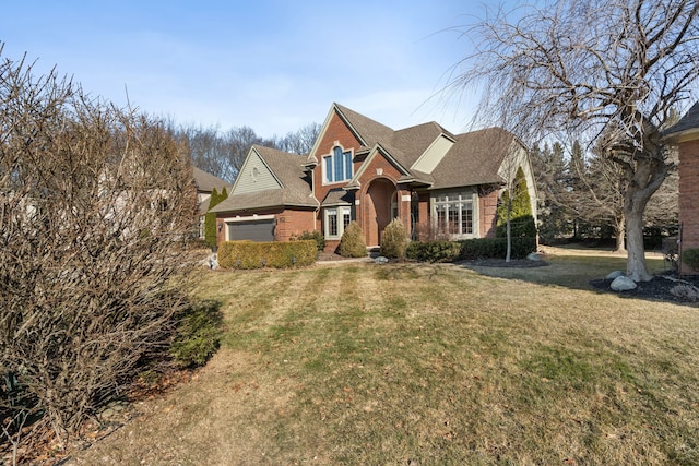 view of front facade with a front lawn, an attached garage, and brick siding