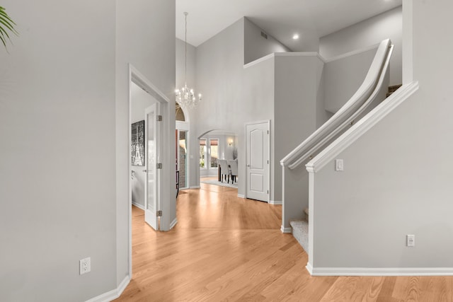 entryway with baseboards, arched walkways, wood finished floors, and stairs