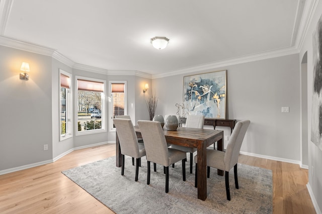 dining area featuring baseboards, crown molding, and light wood-style floors