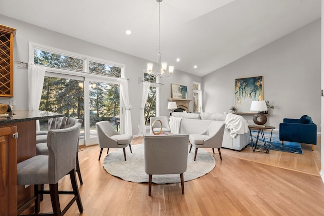 living area featuring high vaulted ceiling, recessed lighting, a fireplace, light wood-type flooring, and a chandelier