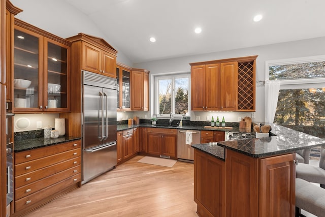 kitchen featuring a kitchen bar, a peninsula, brown cabinets, and stainless steel appliances