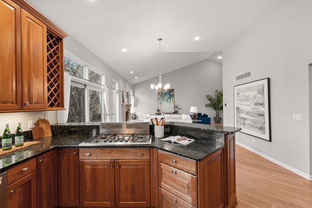 kitchen with visible vents, lofted ceiling, a peninsula, light wood-style floors, and stainless steel appliances