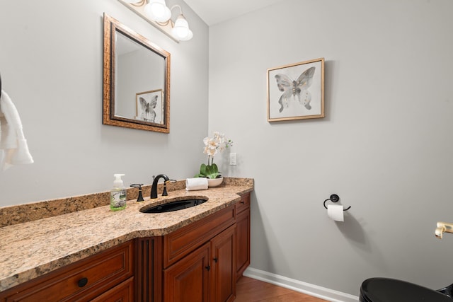 bathroom featuring vanity, wood finished floors, and baseboards