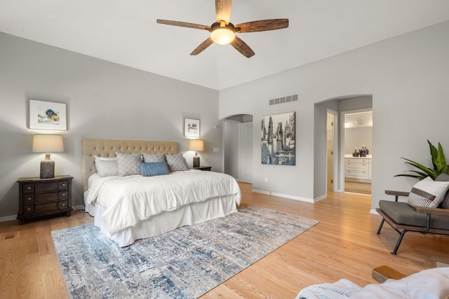 bedroom featuring arched walkways, visible vents, and light wood-style floors