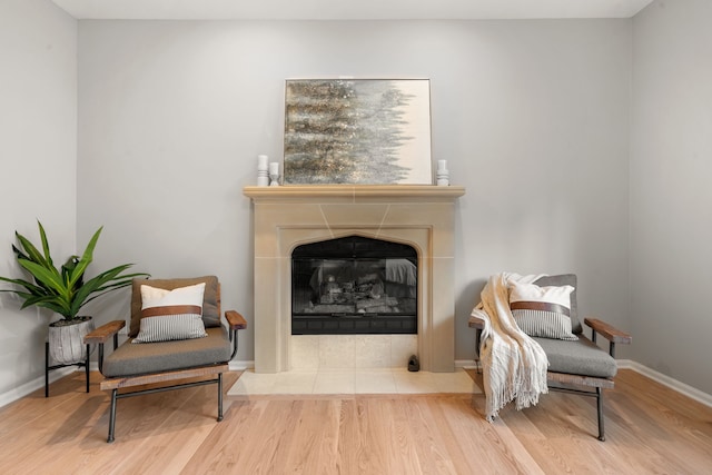 living area with a fireplace, wood finished floors, and baseboards