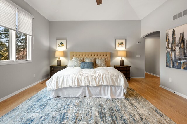 bedroom featuring visible vents, arched walkways, baseboards, and wood finished floors