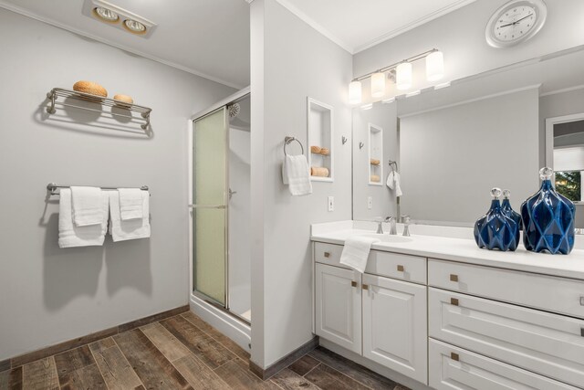 bathroom with vanity, crown molding, a stall shower, and wood finish floors