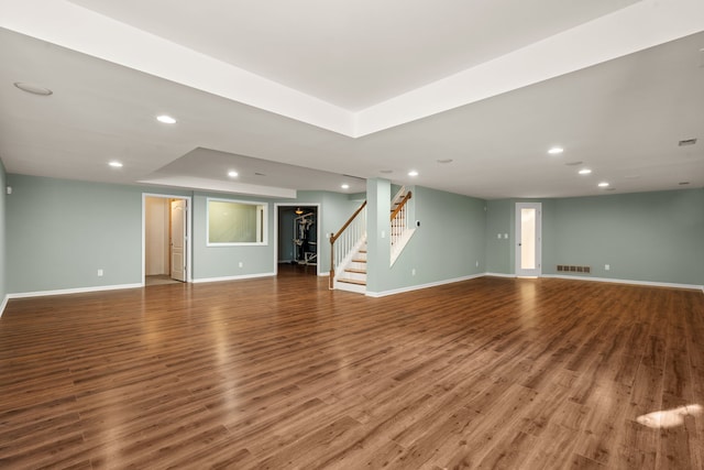 unfurnished living room with recessed lighting, baseboards, wood finished floors, and stairs