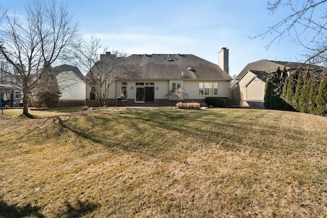 back of property with a yard, roof with shingles, and a chimney