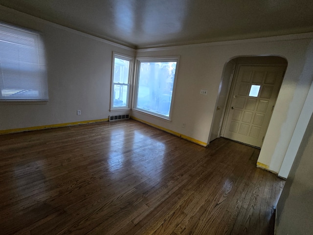 interior space featuring arched walkways, visible vents, baseboards, dark wood finished floors, and crown molding