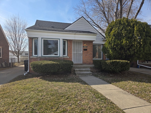 bungalow-style house featuring brick siding, a shingled roof, a front yard, and fence