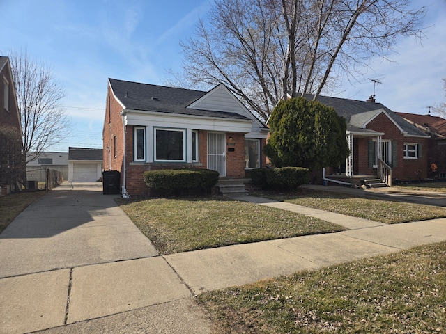 bungalow with an outbuilding, driveway, a detached garage, a front yard, and brick siding