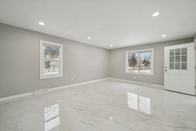 unfurnished room with marble finish floor, visible vents, and baseboards