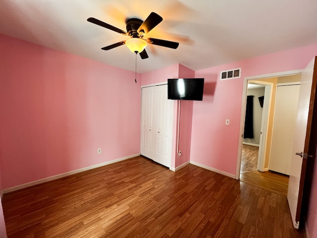 unfurnished bedroom with baseboards, visible vents, ceiling fan, wood finished floors, and a closet