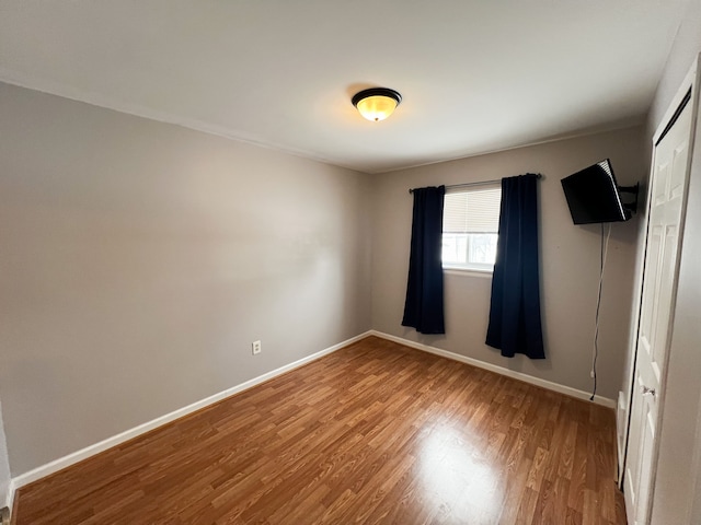 unfurnished bedroom with a closet, baseboards, and wood finished floors