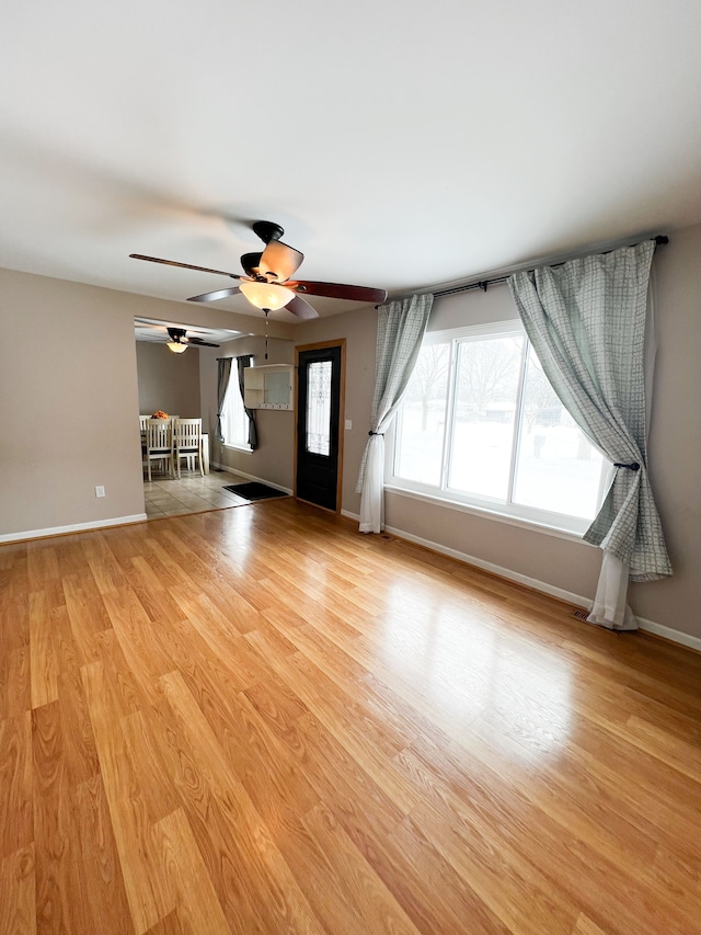 unfurnished living room with baseboards and light wood finished floors