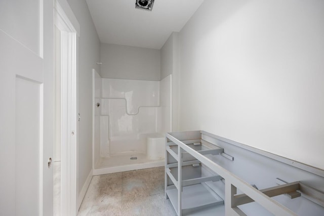 bathroom with concrete flooring, baseboards, and walk in shower