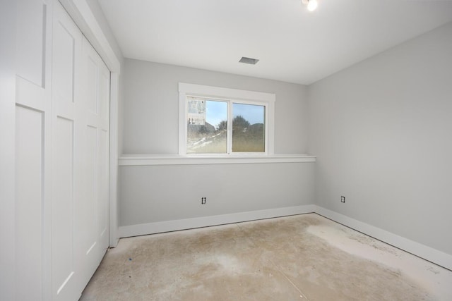 unfurnished bedroom with concrete floors, a closet, visible vents, and baseboards