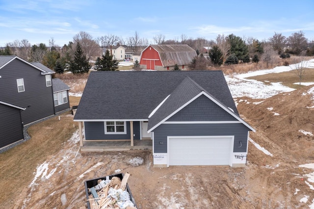 view of front of house with driveway, a shingled roof, and an attached garage