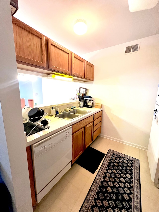 kitchen featuring light countertops, white dishwasher, visible vents, and a sink