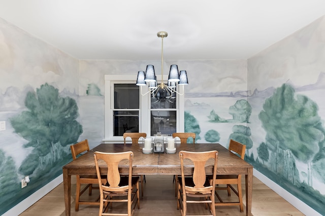 dining area featuring baseboards, wood finished floors, and an inviting chandelier