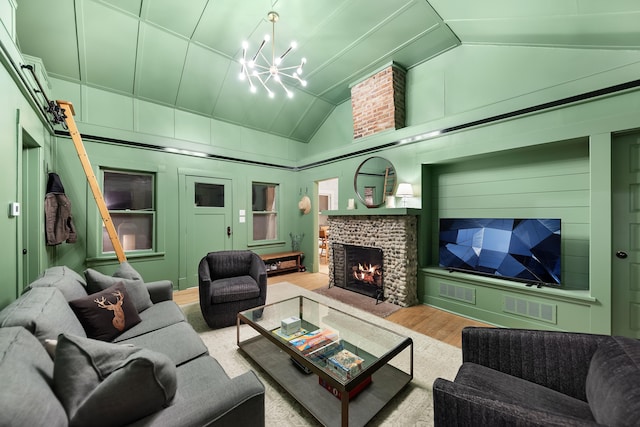 living area featuring visible vents, lofted ceiling, light wood-type flooring, a fireplace, and a chandelier